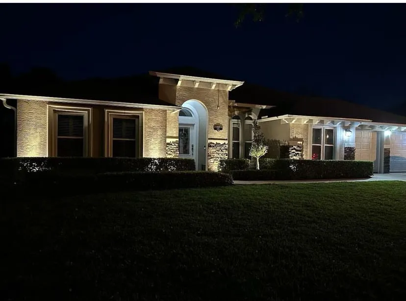 Landscape Lighting A well-lit home with a manicured lawn and colorful landscaping.