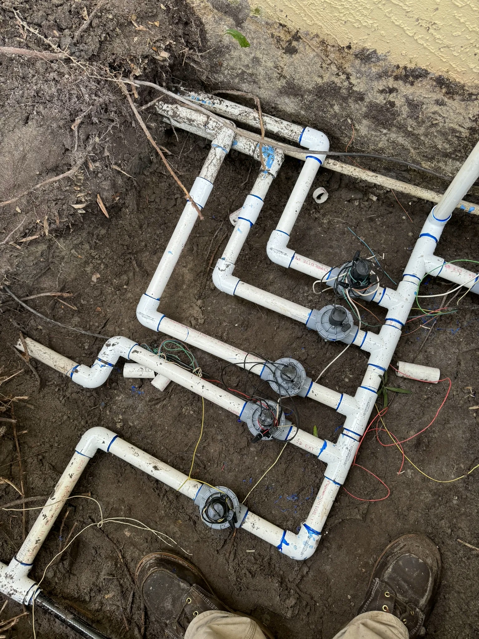 A complex system of underground pipes and electrical wires used to control the flow of water to different zones of a sprinkler system.